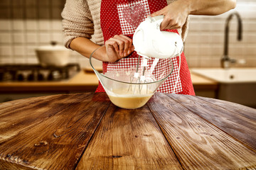 Poster - Woman hands in kitchen making cake. Wooden brown table of free space for your decoration and kitchen interior 