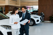 © LIGHTFIELD STUDIOS - attractive woman standing with bearded man and holding papers in car showroom