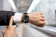 © BillionPhotos.com - Businessman pointing at hand watch on grey
