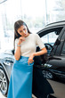 © LIGHTFIELD STUDIOS - young pensive woman standing near black car