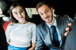 © LIGHTFIELD STUDIOS - selective focus of cheerful woman and man in suit sitting in car