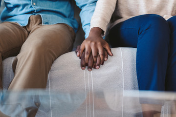 Canvas Print - Young African American couple holding hands on a sofa