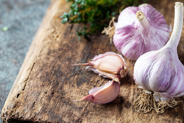 Organic garlic bulbs with garlic cloves on old wooden board