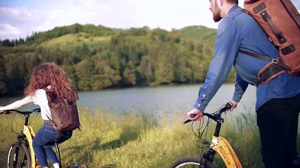 Wall Mural - rear view of young tourist couple travellers with electric scooters in nature.