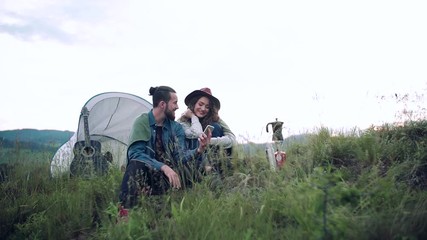 Wall Mural - young tourist couple travellers with smartphone and tent shelter sitting in nature.