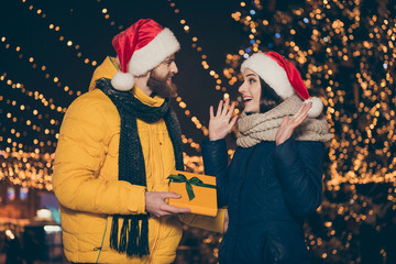 Photo of two people couple husband guy giving excited surprised wife lady his x-mas giftbox newyear noel tradition wear coats santa caps scarfs newyear park outdoors