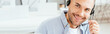 © LIGHTFIELD STUDIOS - panoramic shot of happy operator in brokers agency touching headset and looking at camera