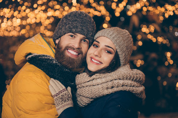 Merry christmas. Photo of two people guy lady in love visit city illuminated park newyear x-mas evening frosty weather stand close wear winter jackets scarfs hats outdoors