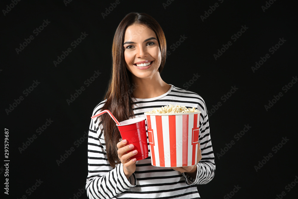 Young woman with popcorn and soda drink on dark background