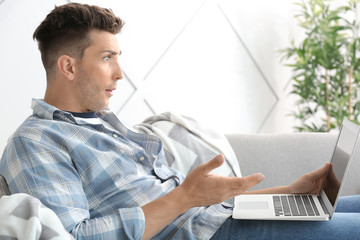 Sticker - Shocked young man with laptop at home