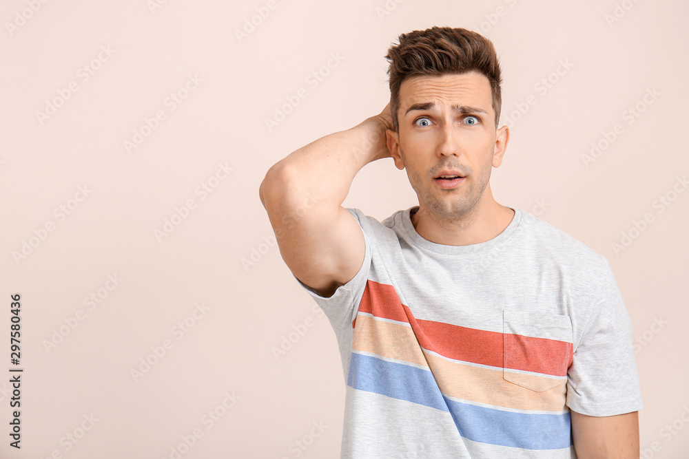 Shocked young man on color background