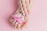 Beautiful stylish trendy female pink manicure with flower on background, top view. Concept beauty