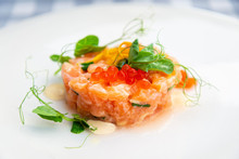 Fresh And Tasty Tartare Of Raw Salmon Prepared With Salmons Eggs And Vegetables On Top Served In White Plate
