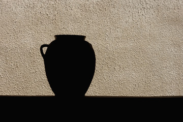 Blurred silhouette of clay pot on the background of the plastered wall