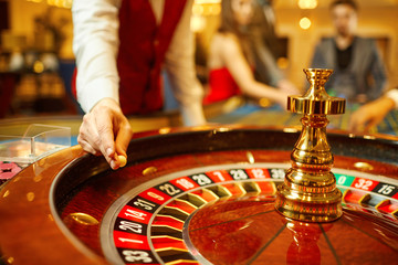 Sticker - The croupier holds a roulette ball in a casino in his hand.