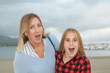 © NomadCam - Mother and daughter looking at the camera with an expression of surprise next to the sea