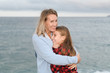 © NomadCam - Mother and daughter hugged and happy show their affection next to the sea