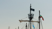 Mast Ship With A Pirate Flag On A Background Of Clear Blue Sky