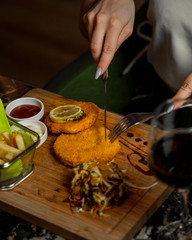 Wall Mural - woman cutting chicken patties served with fries, fresh salad