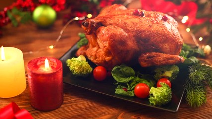 Wall Mural - Christmas Roasted Chicken Dinner. Winter Holiday table served, decorated with candles. Delicious Steamed Roast chicken over wooden background with Christmas gifts, table setting. Dolly shot 4K UHD