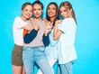 © halayalex - Four young beautiful smiling hipster girls in trendy summer clothes. Sexy carefree women posing near blue wall in studio. Positive models having fun and hugging