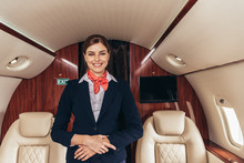 Smiling Flight Attendant In Uniform Looking At Camera In Private Plane