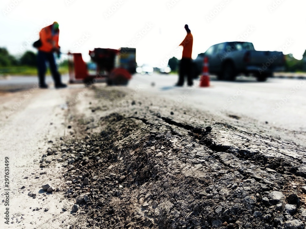The paved road is damaged. And there are workers fixing the road