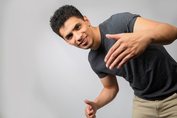 Young Hispanic man dancing and inviting to have fun- man in studio smiling