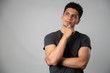 © Fernanda - Young Hispanic man thinking with his hand on his chin- man having an idea - portrait in studio with gray background