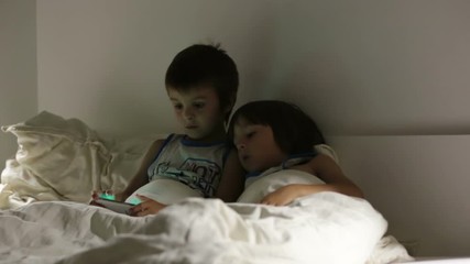 Wall Mural - First grade boy, reading a bedtime story book to his younger brother