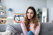 © BestForYou - Happy young woman holding clock.