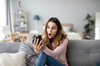 © BestForYou - Upset young woman with an alarm clock on the couch.