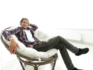 serious guy rests sitting in a large comfortable chair. side view.