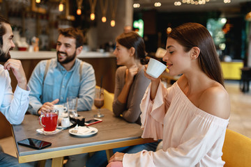 Sticker - Young woman enjoys coffee with friends in a cafe