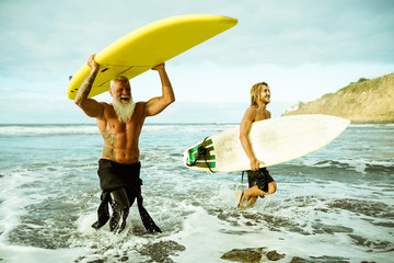 Best friends doing surfing in the summer time . People going out into the ocean. Sporty people lifestyle and extreme sport concept - Image