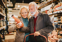 Happy Senior Couple Shopping In Grocery Store Or Supermarket. Consumerism Concept.