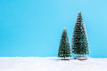 Winter theme with miniature Christmas trees on blue background with copy-space