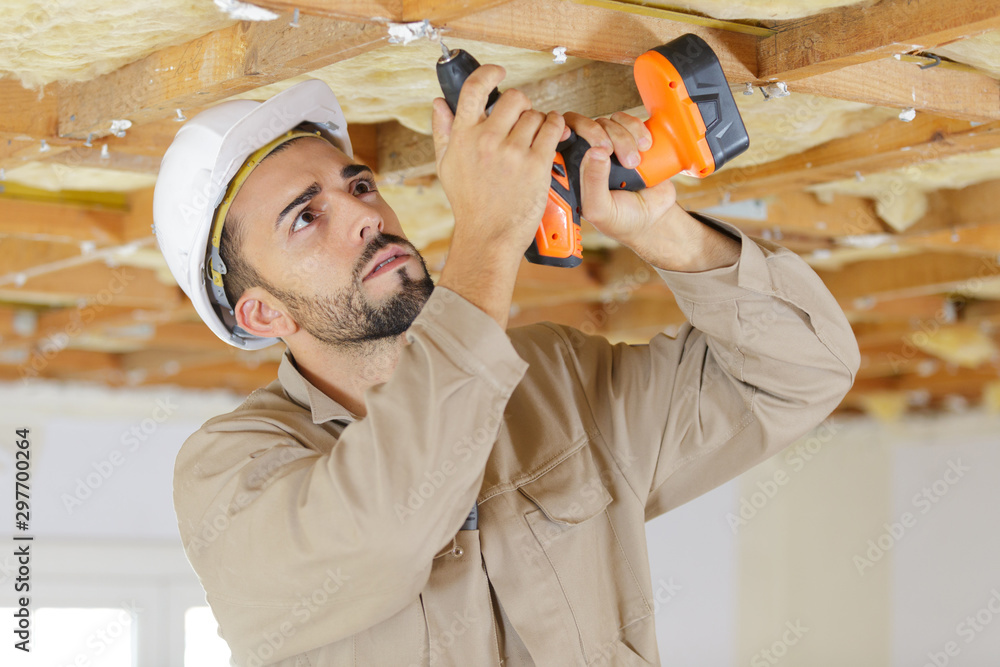builder using cordless drill on wooden ceiling - obrazy, fototapety, plakaty 