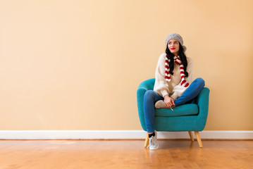 Young woman in a cold weather winter outfit sitting in a chair