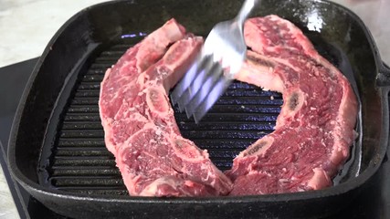 Canvas Print - Placing steaks in a cast iron grill