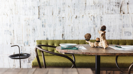 Poster - Dining area decorated with green sofa, wooden top table, black steel chair and white scratch texture wallpaper. Modern interior restaurant atmosphere.