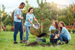 © Viktoriia - Volunteering. Young people volunteers outdoors planting trees pouring out fertilizer into pit happy motion