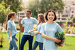 © Viktoriia - Volunteering. Young people volunteers outdoors planting trees asian girl standing with pot laughing happy close-up blurred background