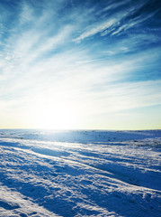 Wall Mural - low sun in dramatic clouds over meadow with snow in winter