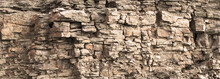 Rock Cliff Face Background. Toned. Wild Stone Protruding Crumbling Layered Blocks In Quarry. Abstract Texture For Stone Mining Industry. Copy Space For Custom Text. Front View
