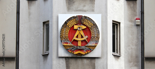 Fotomural National emblem of East Germany (DDR) on a wall in Berlin near Checkpoint Charli
