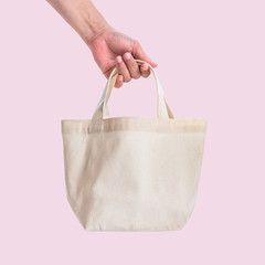 Tote bag canvas white cotton fabric cloth for eco shoulder shopping sack mockup blank template isolated on pink background (clipping path) with woman’s hand handling handle straps