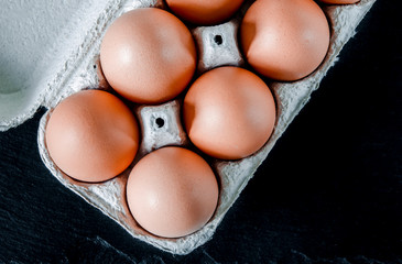 Large brown chicken eggs lie in an eco-friendly cardboard egg tray