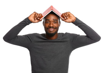 Wall Mural - Portrait of handsome African-American man with book on white background