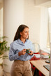 © JustLife - Young businesswoman drinking coffee in office